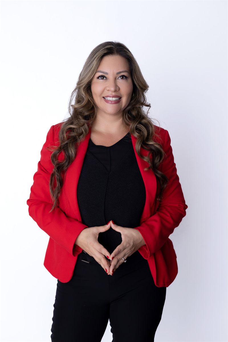 Lina Hernández con blazer rojo y las manos unidas al frente, sonriendo